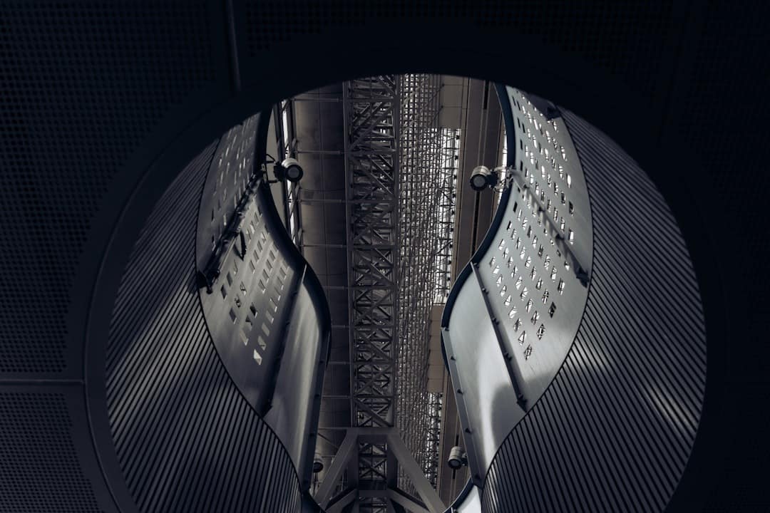 Circular view into a large metallic industrial shaft with panels, lattice beams, and overhead support structures