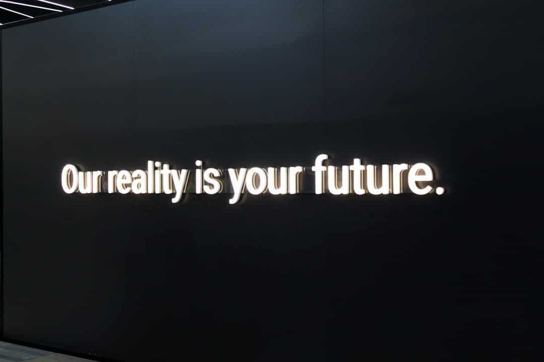 Black wall with bright white illuminated text: 'Our reality is your future.'
