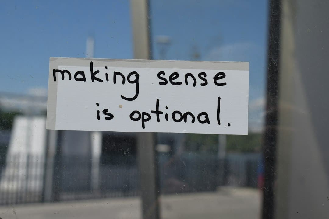 Handwritten sign on a glass window reads 'making sense is optional'.